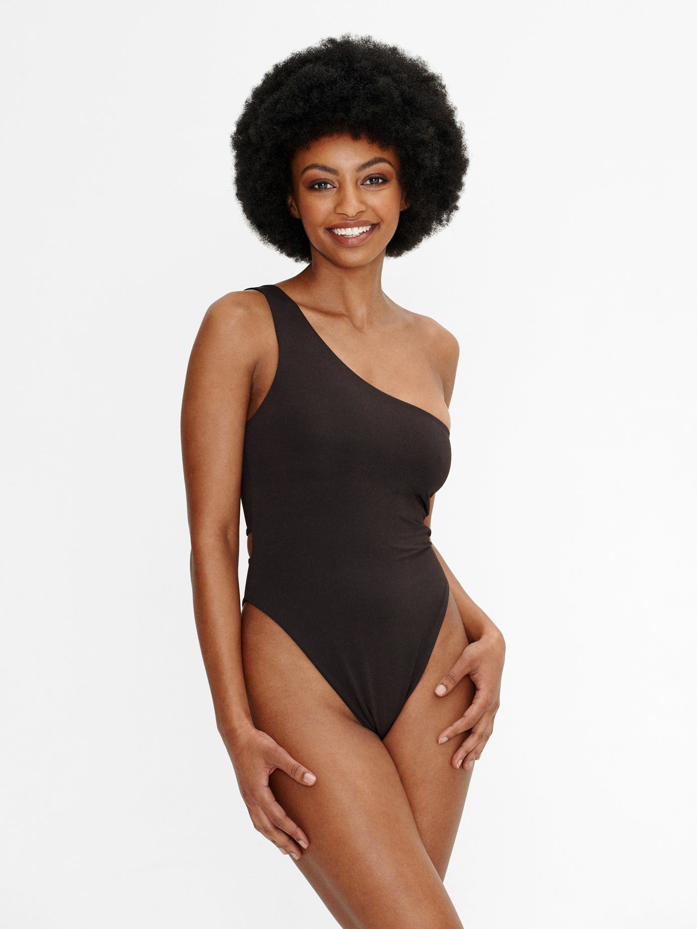 Woman wearing the Kaiserin Amie Swimsuit – Coffee, featuring a one-shoulder design, high-cut leg, and seamless deep brown fabric with a clean, minimal finish.